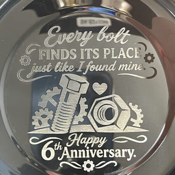 A custom engraved magnetic parts tray features a design with a bolt, nut, gears, and hearts alongside the message: “Every bolt finds its place just like I found mine. Happy 6th Anniversary.”.