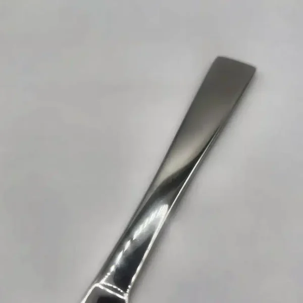A close-up of the handle of the Premium 9.5 Inch Personalized Butter Knife, made from shiny stainless steel and placed on a white surface.