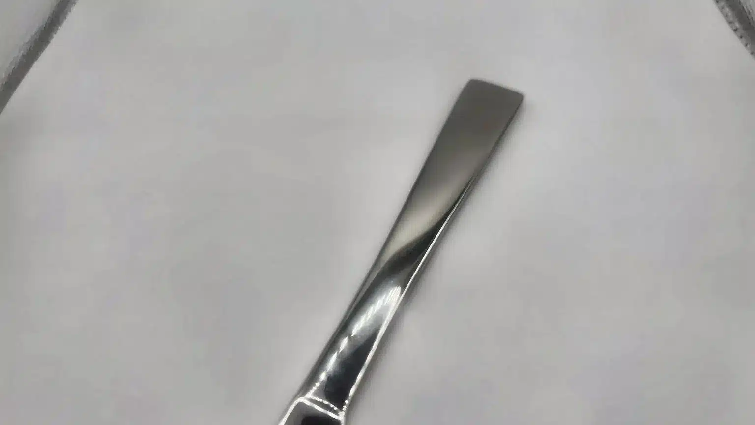 A close-up of the handle of the Premium 9.5 Inch Personalized Butter Knife, made from shiny stainless steel and placed on a white surface.