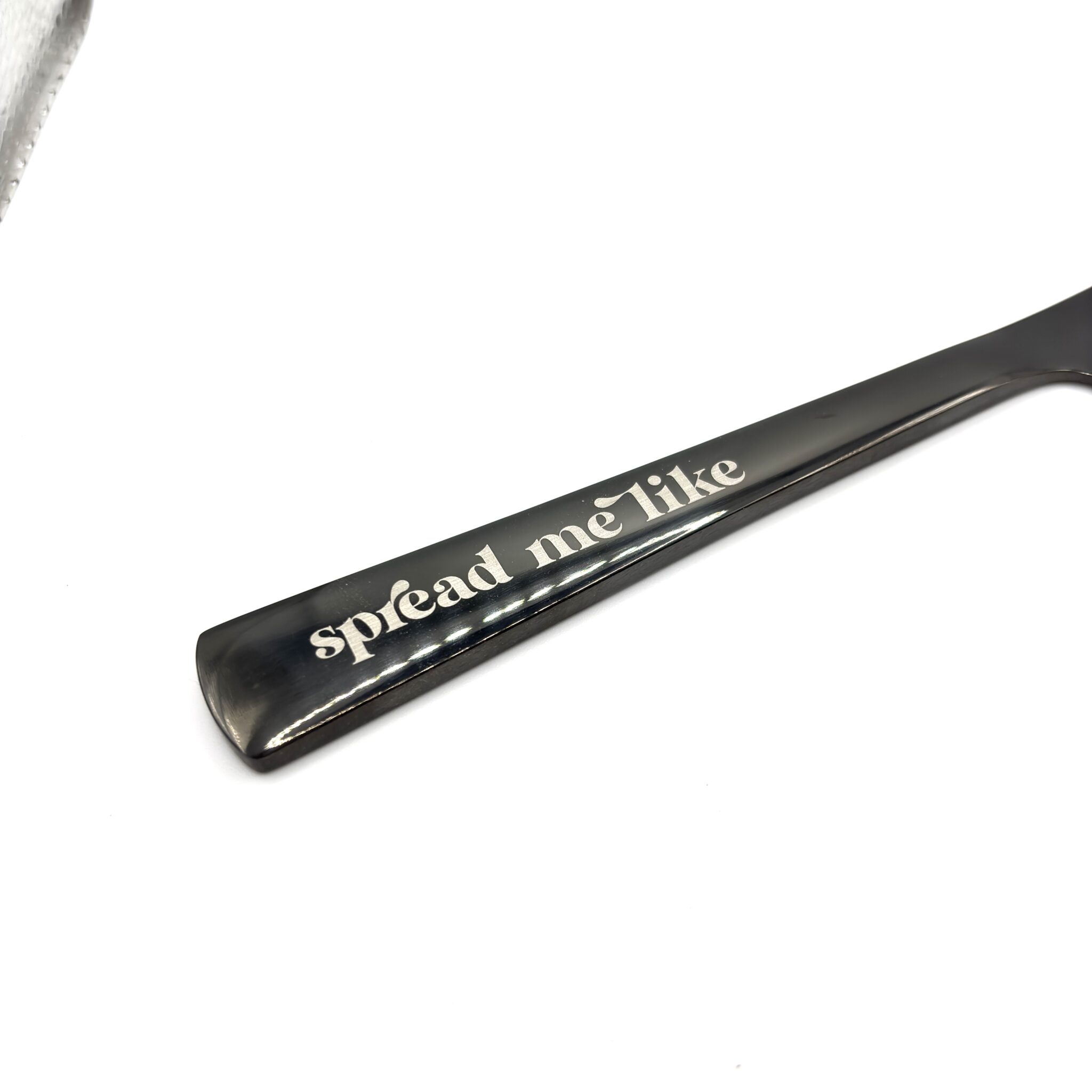 A close-up of the 9" Custom Engraved Black Knife handle with "spread me" playfully engraved in lowercase letters, shown against a white background.