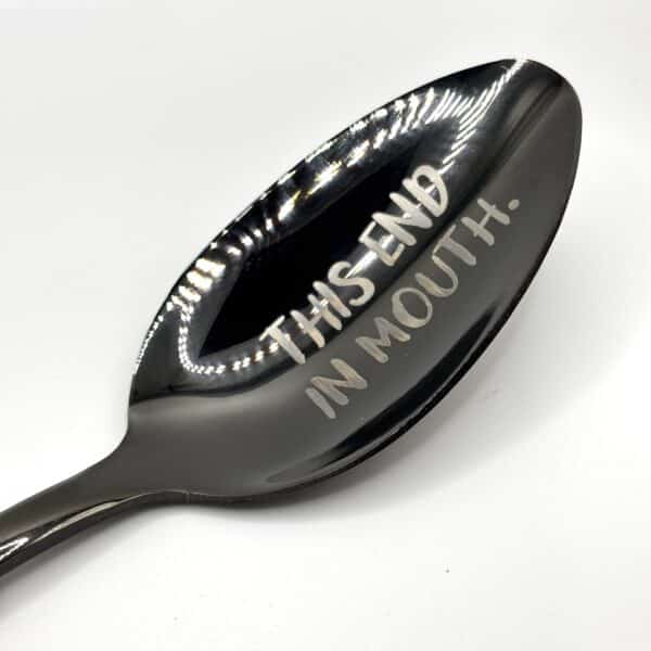 An 8.75" Custom Black Engraved Spoon with "THIS END IN MOUTH." engraved on the bowl, displayed against a white background.