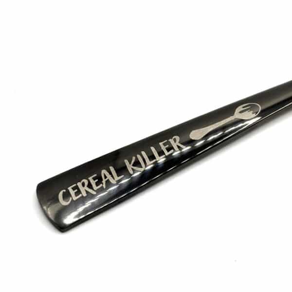 The 8.75" Custom Black Engraved Spoon features a playful handwritten-style inscription, "CEREAL KILLER," beside a small spoon image engraved on the metal handle.