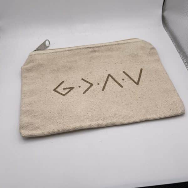 A Custom Engraved Natural Canvas Zipper Pouch, featuring abstract brown symbols or letters printed on one side, lies on a white surface.