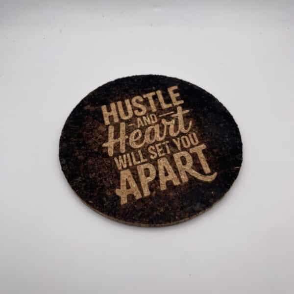 A square, 0.20″ thick photo cork coaster featuring the engraved words “Hustle and Heart Will Set You Apart” in bold, light-colored text, displayed on a plain white background.