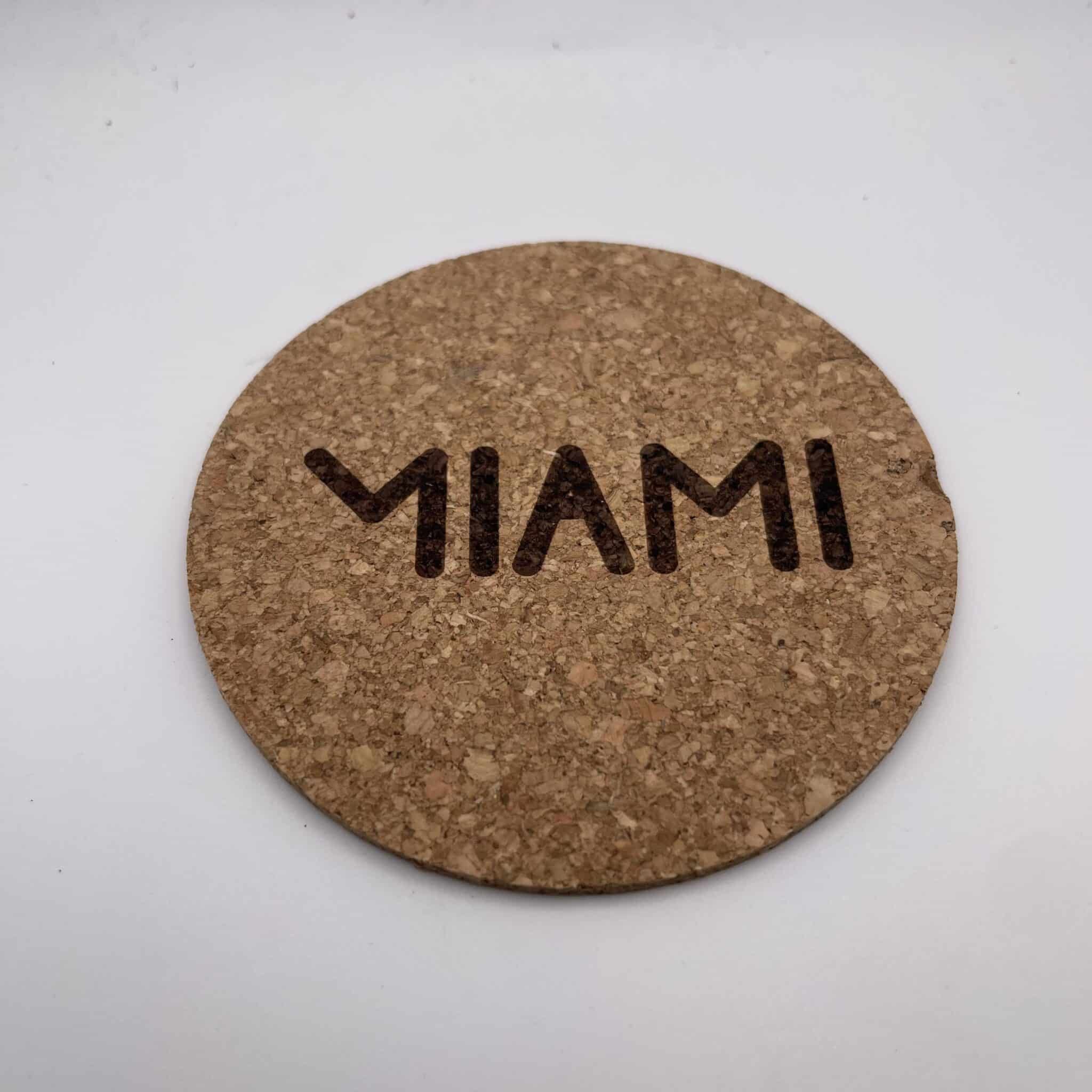 Close-up of a round cork coaster on a white background, showing a row of dark holes along its lower edge.