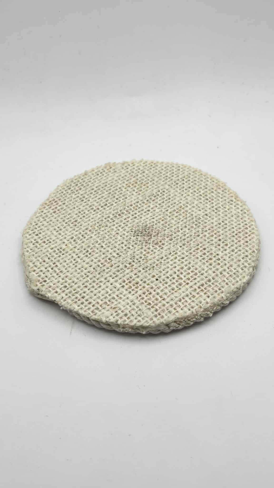 A round, flat, woven beige pad with a slightly uneven edge, placed on a plain white background.